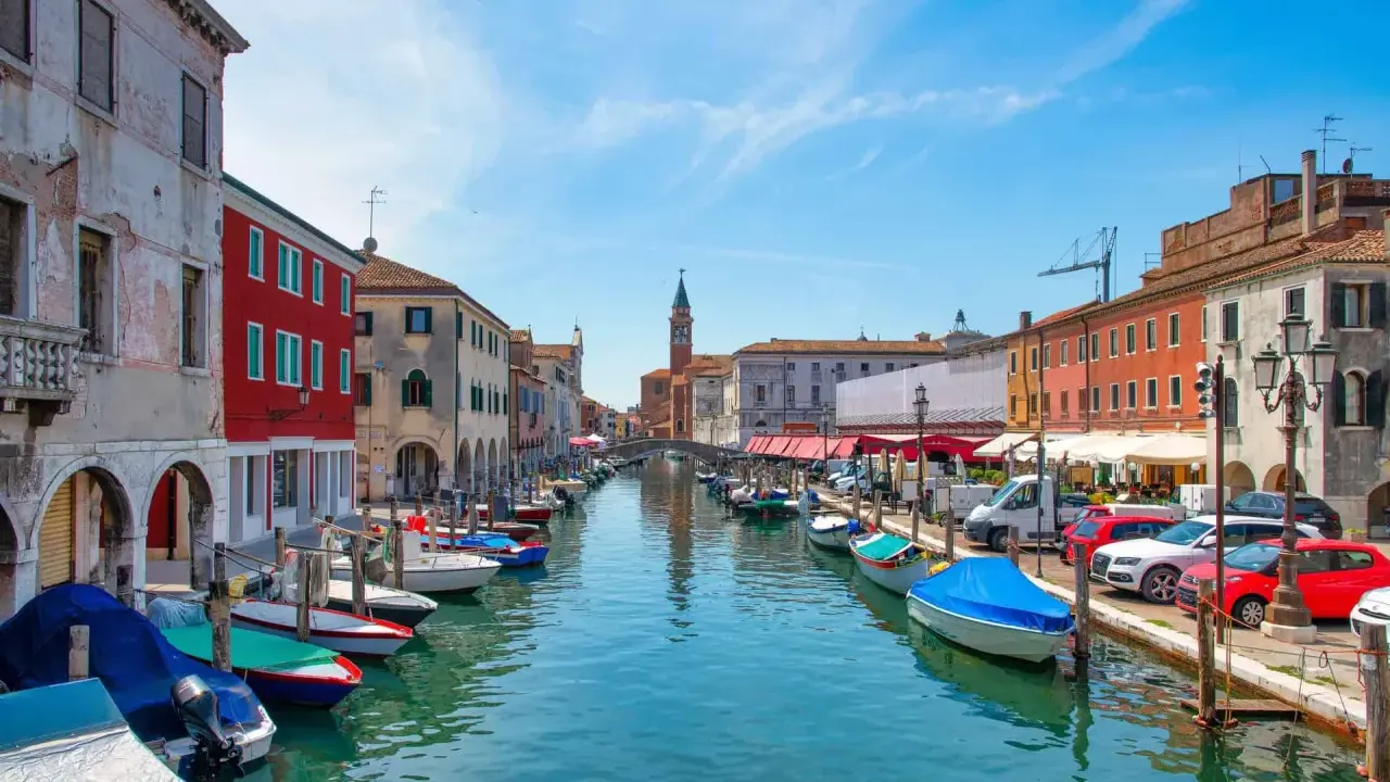 Vue d'un canal à Chioggia, Venise, avec des bateaux amarrés le long des maisons colorées.
