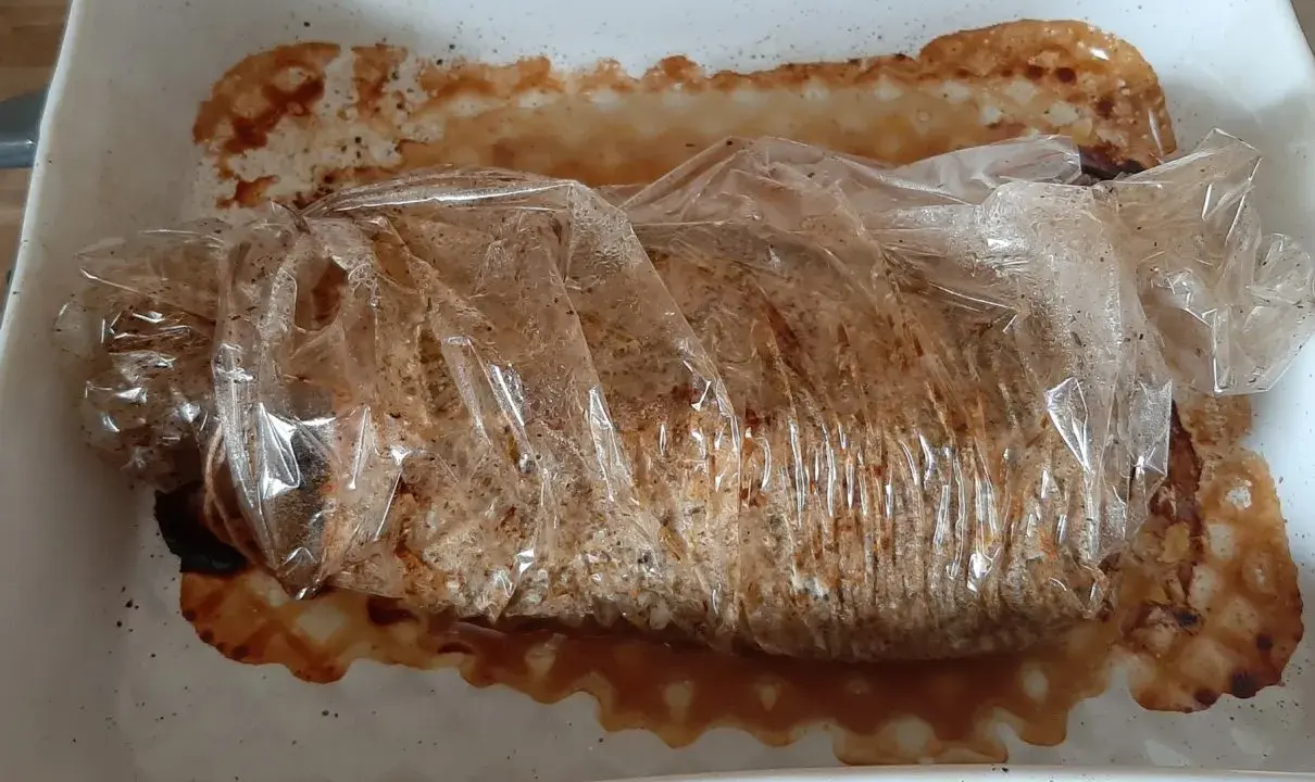 Schab pieczony w rękawie, soczysty i aromatyczny, w naczyniu żaroodpornym z wytopionym tłuszczem.