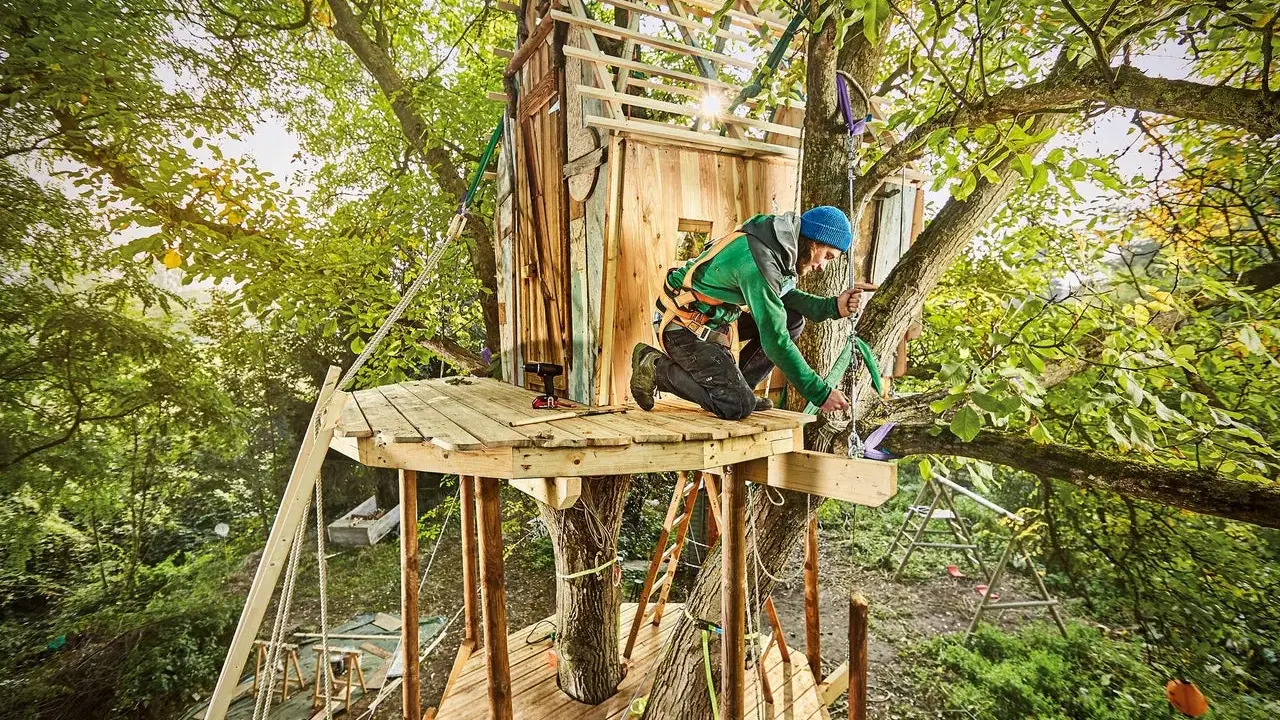 Mann baut Baumhaus für Kinder. Tolle baumhaus kinder ideen für Abenteuer im Grünen.