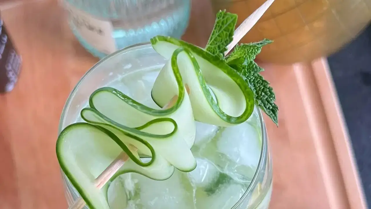 Un gin tonic concombre rafraîchissant, garni de fines lamelles de concombre en spirale et de feuilles de menthe fraîche.