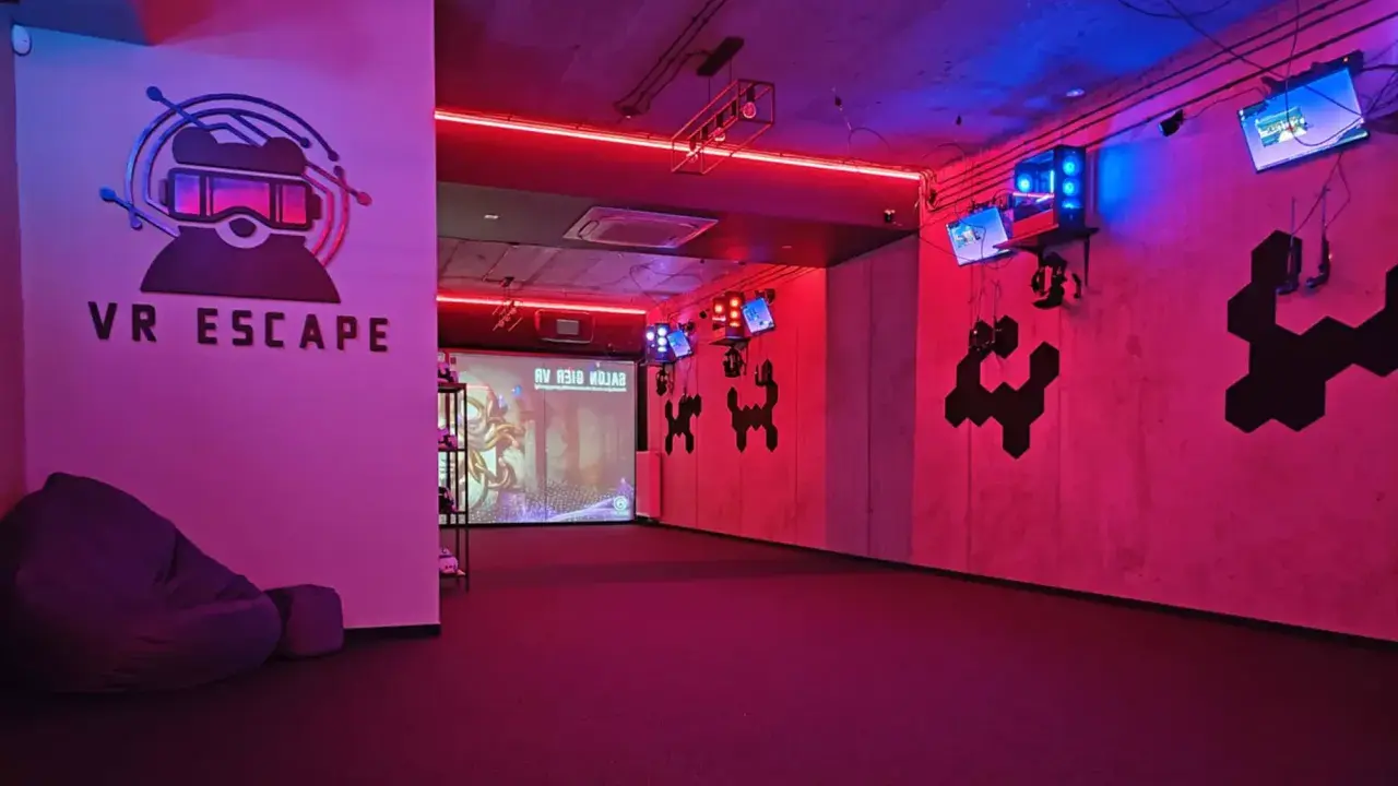 Częstochowa escape room z neonowym oświetleniem, logo VR ESCAPE i ekranem projekcyjnym.