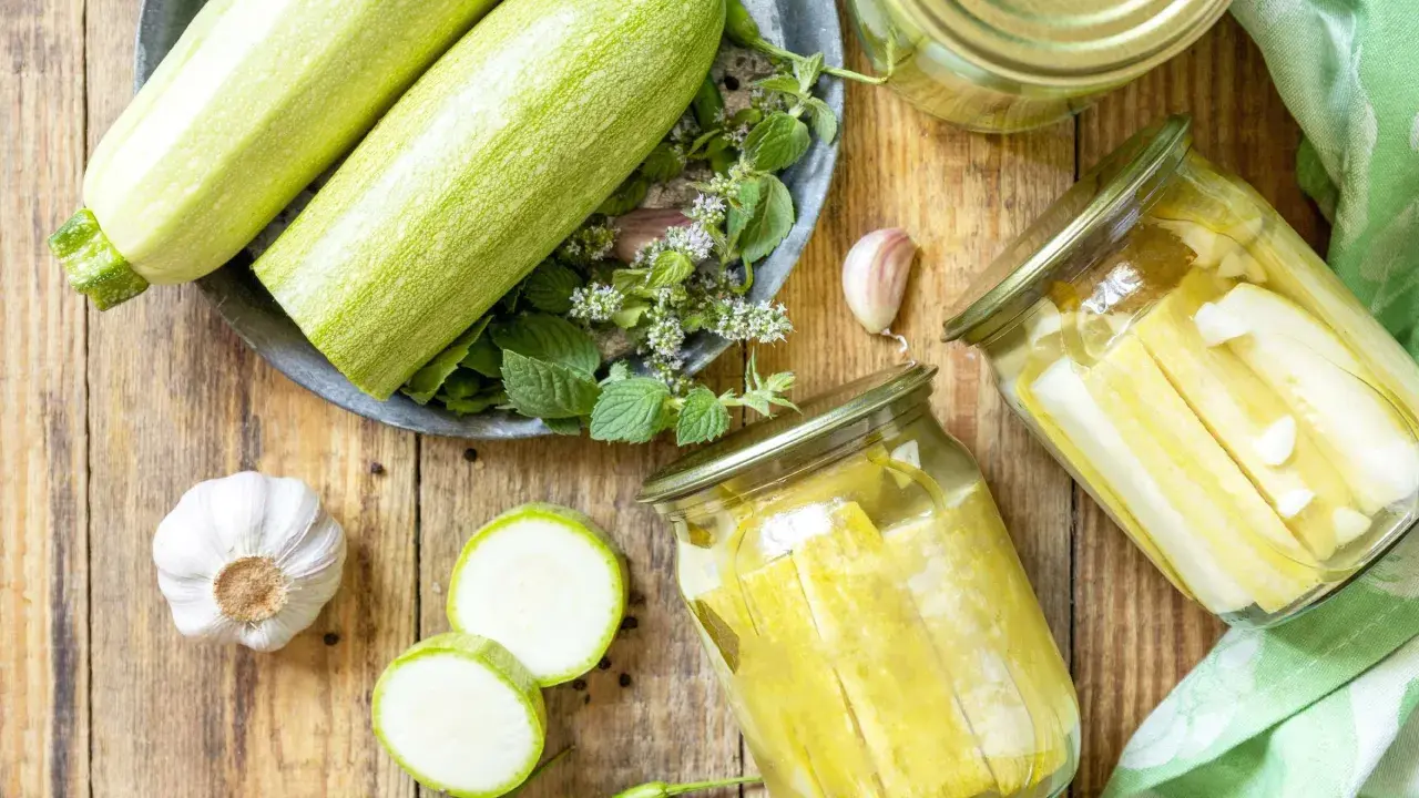 Zucchini haltbar machen: Frische Zucchini, Knoblauch, Chili und Kräuter für die Konservierung in Gläsern.