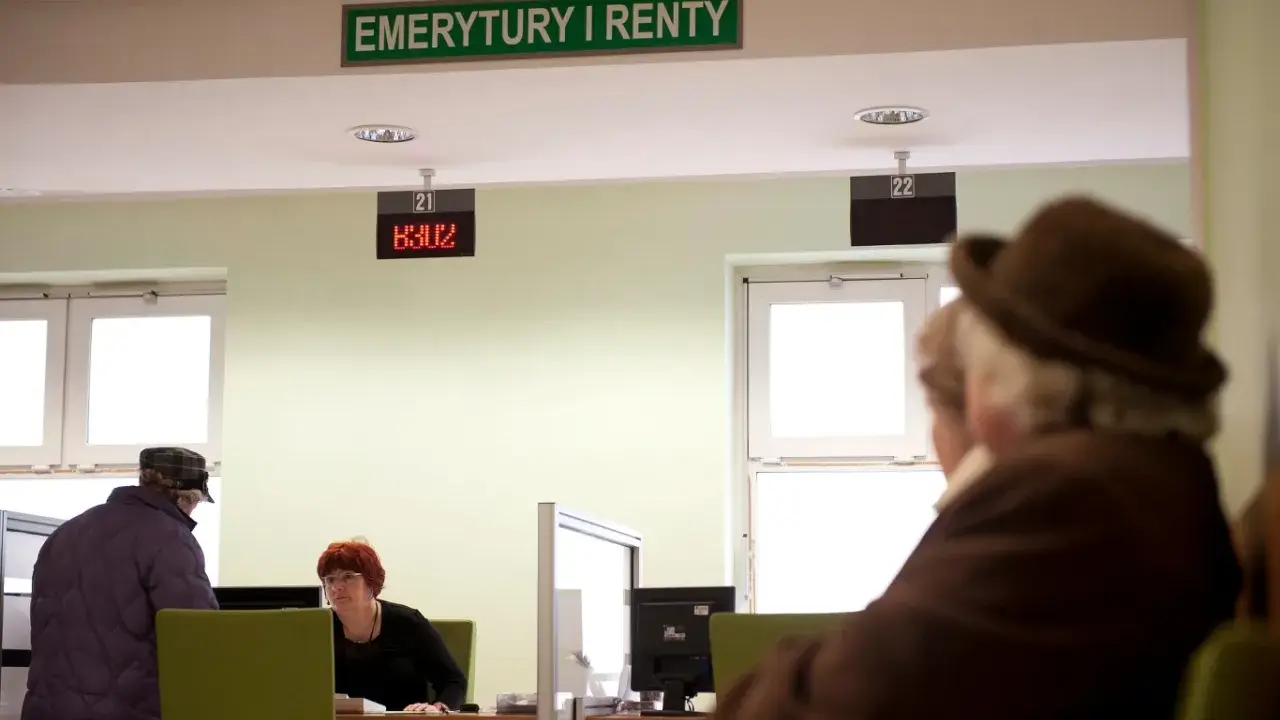 Ludzie czekają na obsługę w urzędzie "Emerytury i Renty". Zastanawiają się, w jakim miesiącu najlepiej przejść na emeryturę.