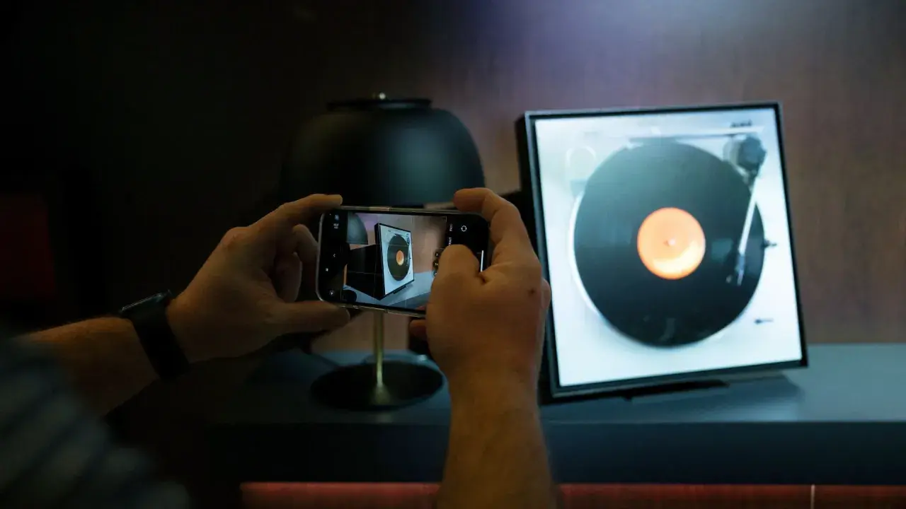 Ręce trzymają smartfon, fotografując gramofon. Odkryj gadżety do domu, o których nie miałeś pojęcia, jak ten nowoczesny sposób na docenienie klasycznej muzyki.