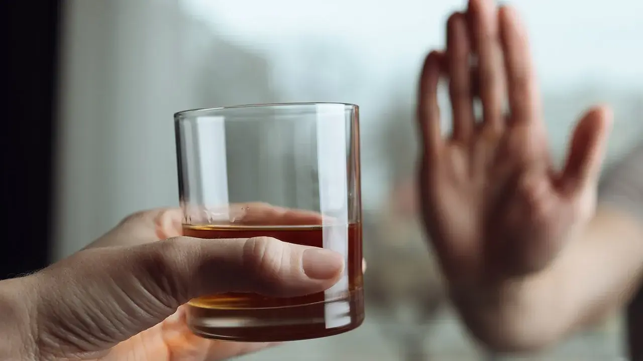 Dłoń odrzuca szklankę z alkoholem, symbolizując decyzję o zerwaniu z nałogiem. To koniec drogi, która mogła prowadzić do zgonu po esperalu.