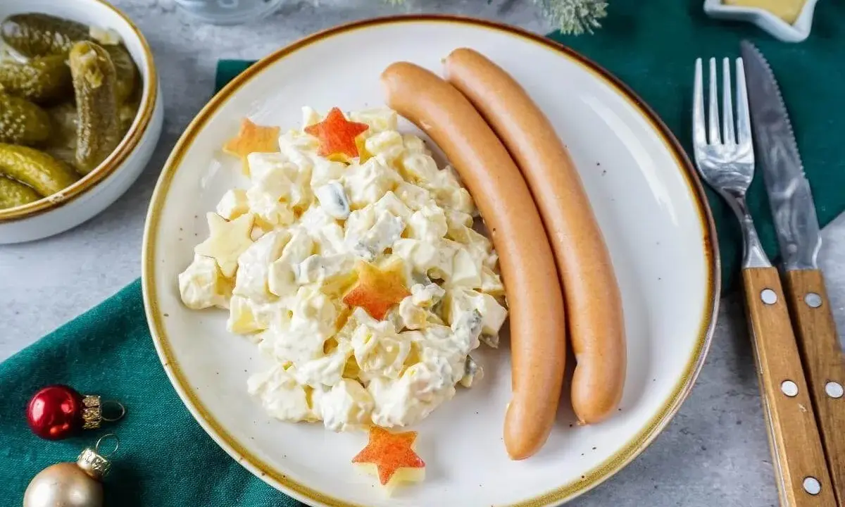 Kartoffelsalat mit Würstchen, dekoriert mit Sternen – ein Klassiker der 10 besten Weihnachtsessen. Dazu gibt es Gewürzgurken und Senf.