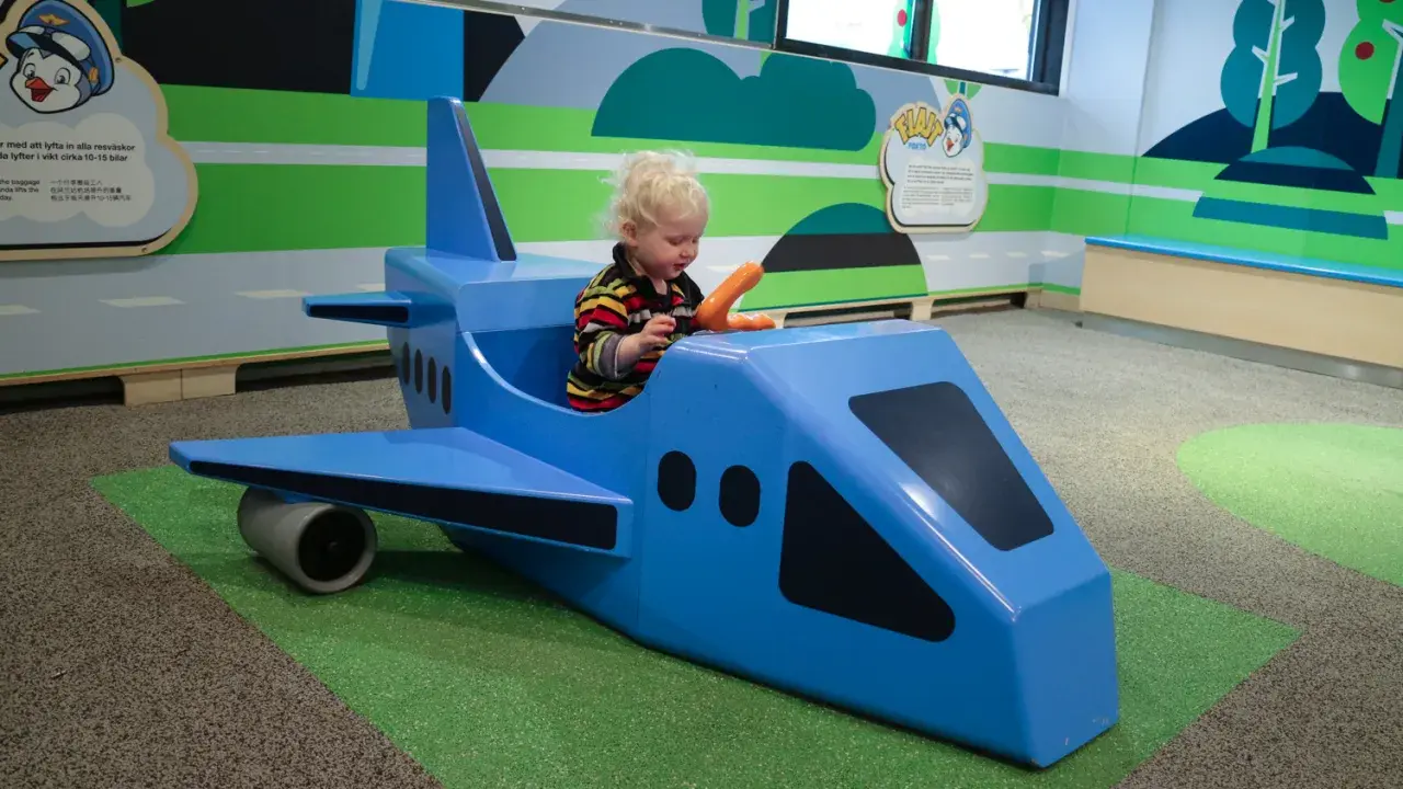 Liten pojke leker i ett blått leksaksplan. En rolig resa med bebis börjar här!