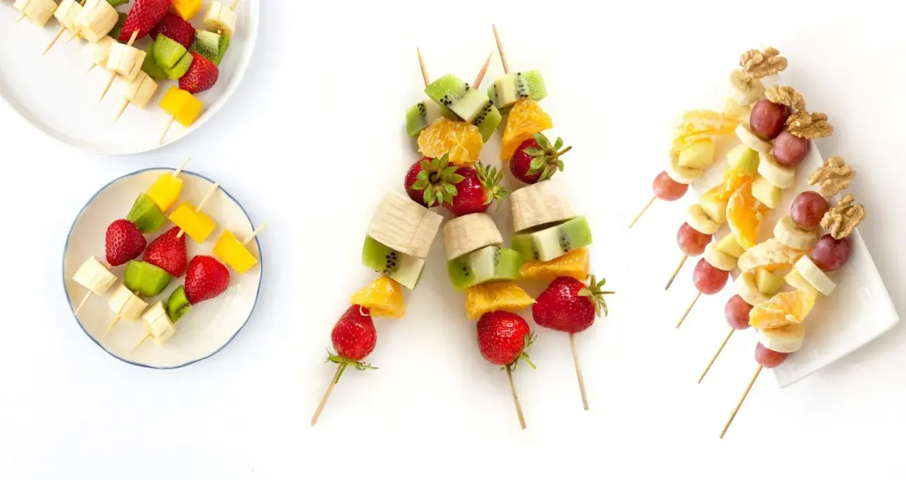 Brochetas de frutas coloridas con fresas, kiwi, plátano, mango, naranja, uvas y nueces. ¡Un postre refrescante y saludable!