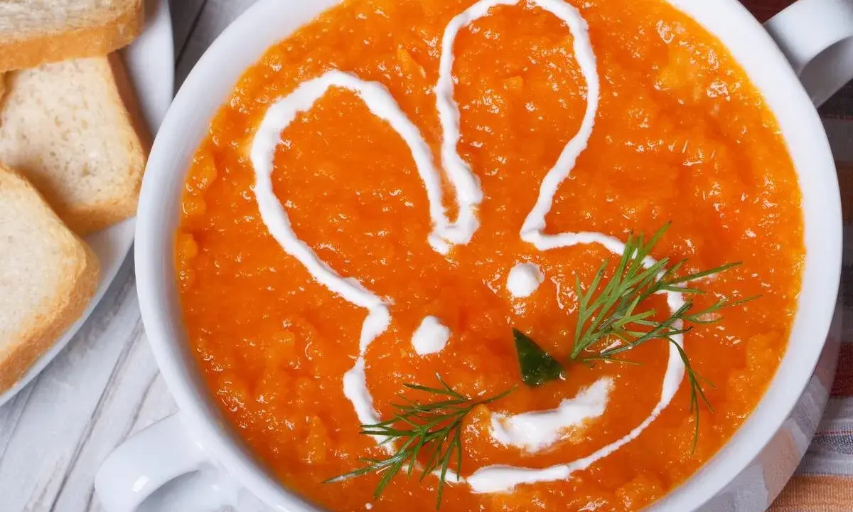 Pomarańczowa marchwianka z ryżem na biegunkę, ozdobiona śmietaną w kształcie królika. Podana z grzankami.