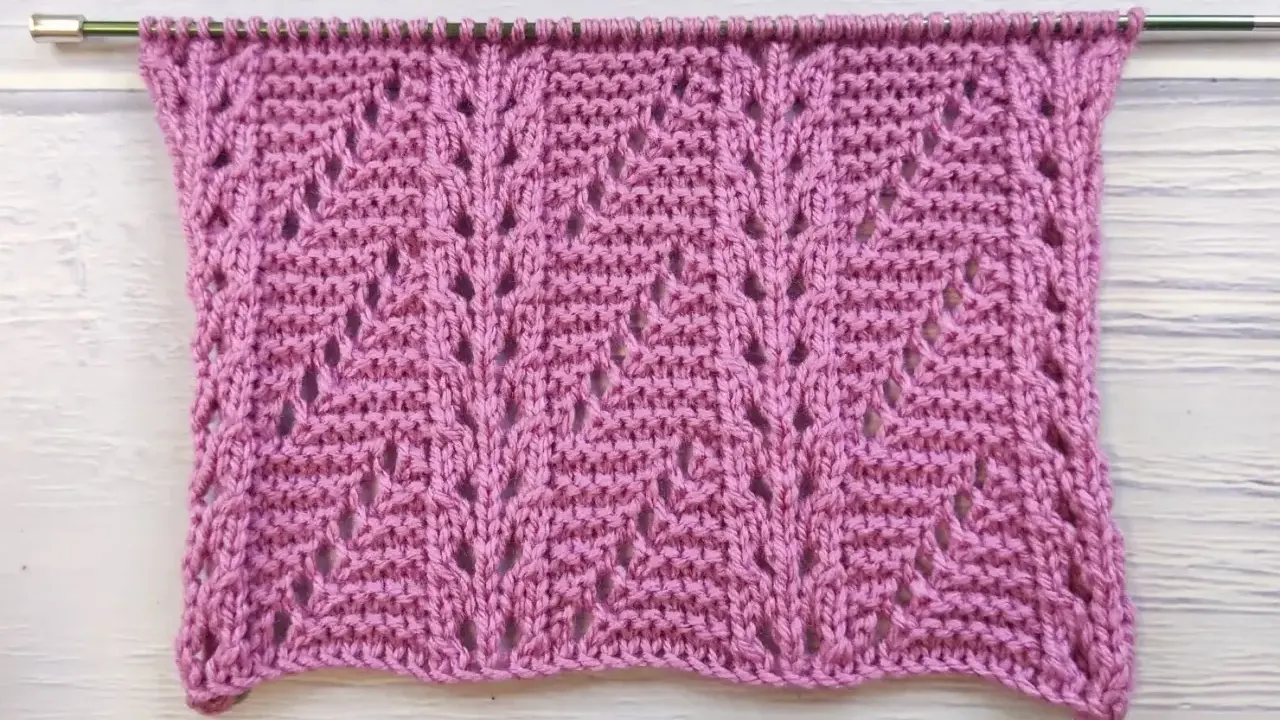 Muestra de tejido con puntos fantasía crochet en color rosa, con un patrón de hojas caladas.