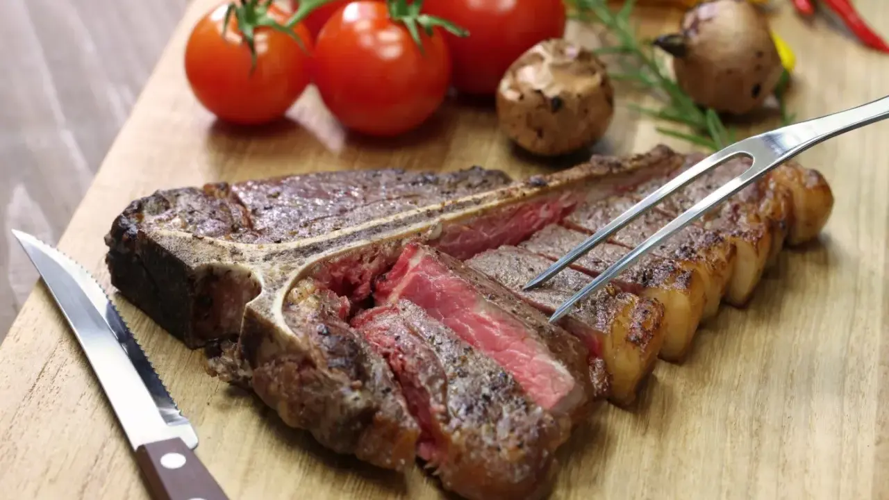 Una succulenta bistecca alla fiorentina, tagliata e pronta per essere gustata. Perfetta per scoprire dove mangiare la fiorentina a Firenze.