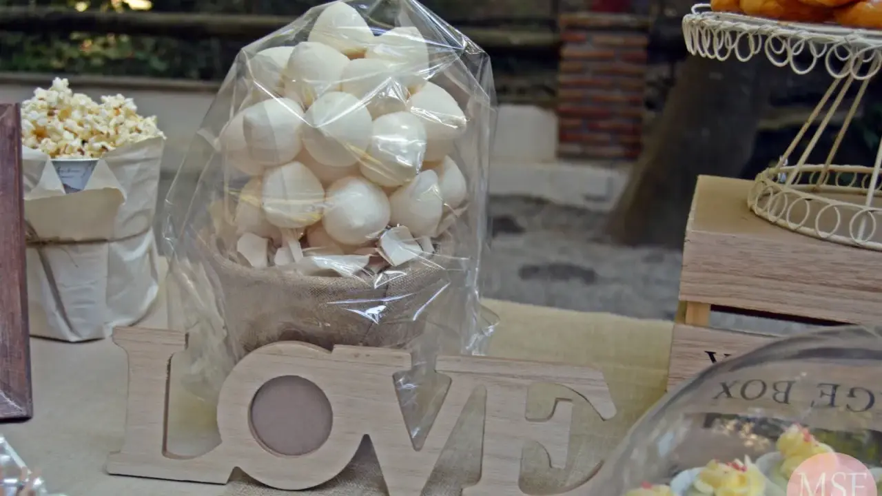 Mesa dulce con palomitas, merengues, cupcakes y letras de madera "LOVE".