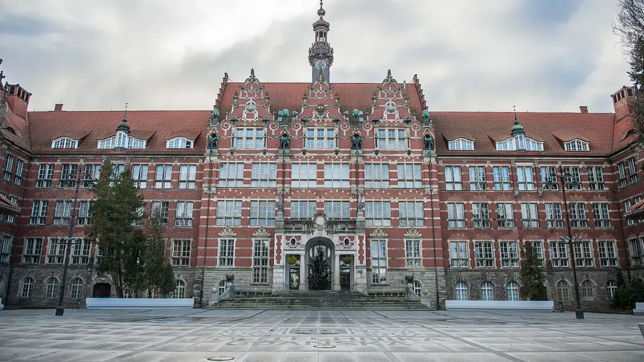 Imponujący budynek Politechniki Gdańskiej, jednej z ważnych uczelni Gdańsk, z charakterystyczną wieżą zegarową i ozdobną fasadą.