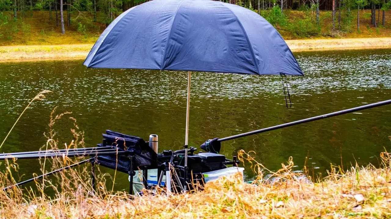 Parasol na ryby chroniący sprzęt wędkarski nad jeziorem.