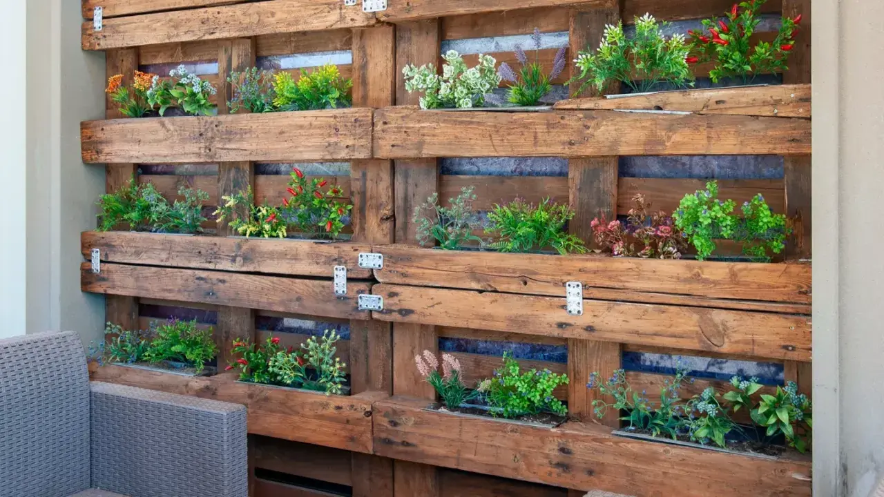 Un **jardín vertical con palets** luce plantas verdes y rojas en un diseño rústico.