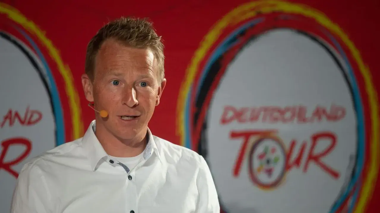 Fabian Wegmann spricht vor dem Logo der Deutschland Tour. Seine Vergangenheit mit Doping-Vorwürfen wirft einen Schatten auf seine Karriere.