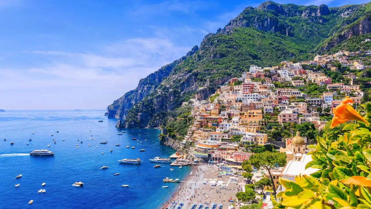 Färgstarka hus klättrar uppför bergssluttningen vid en livlig strand. Perfekt för din resa till Italien tips!