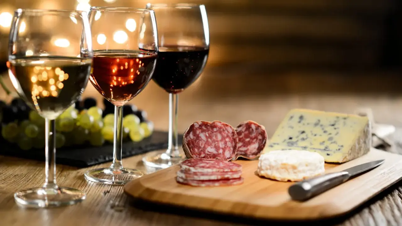 Trois verres de vin, blanc, rosé et rouge, accompagnent un plateau de fromages et charcuteries. La question est : quel vin avec le fromage ?