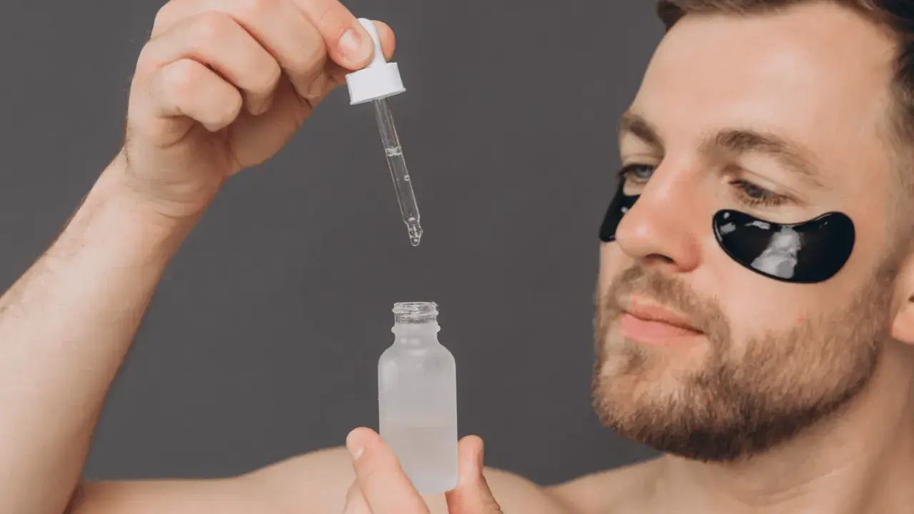 Homme appliquant un sérum, se demandant acide glycolique combien de fois par semaine. Patchs noirs sous les yeux pour un soin ciblé.