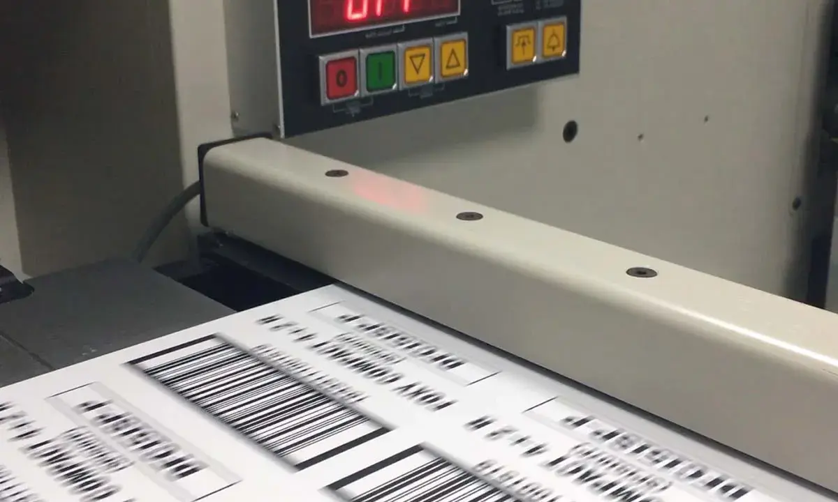 Máquina de impresión offset digital procesando etiquetas con códigos de barras.