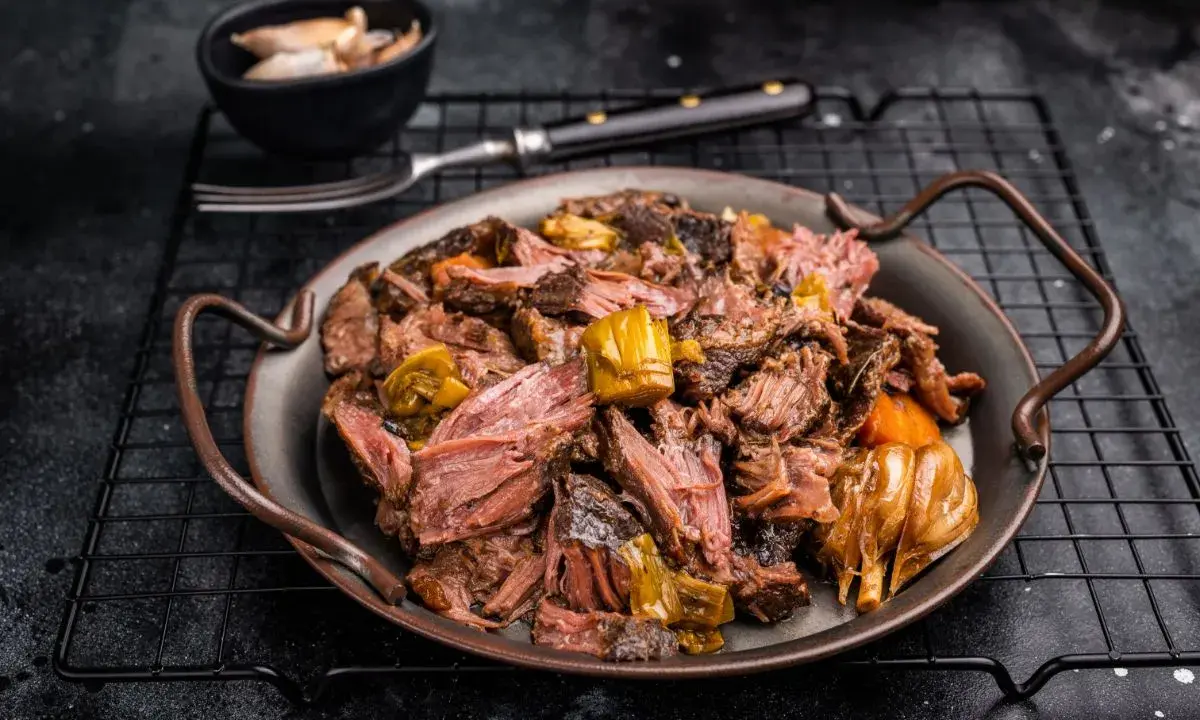 Joue de bœuf effilochée, tendre et savoureuse, servie avec des légumes fondants. Un délice pour les amateurs de viande.