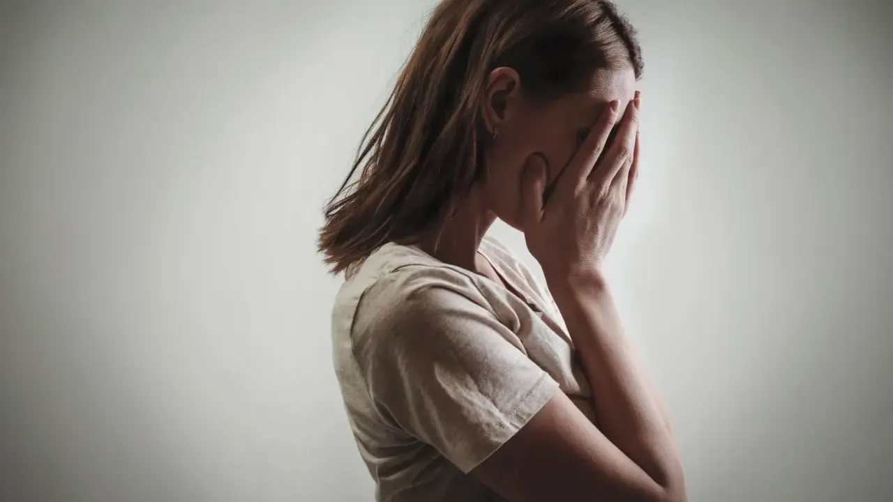 Kobieta zakrywa twarz dłońmi, co może symbolizować różne psychozy objawy, takie jak przytłoczenie czy izolacja.