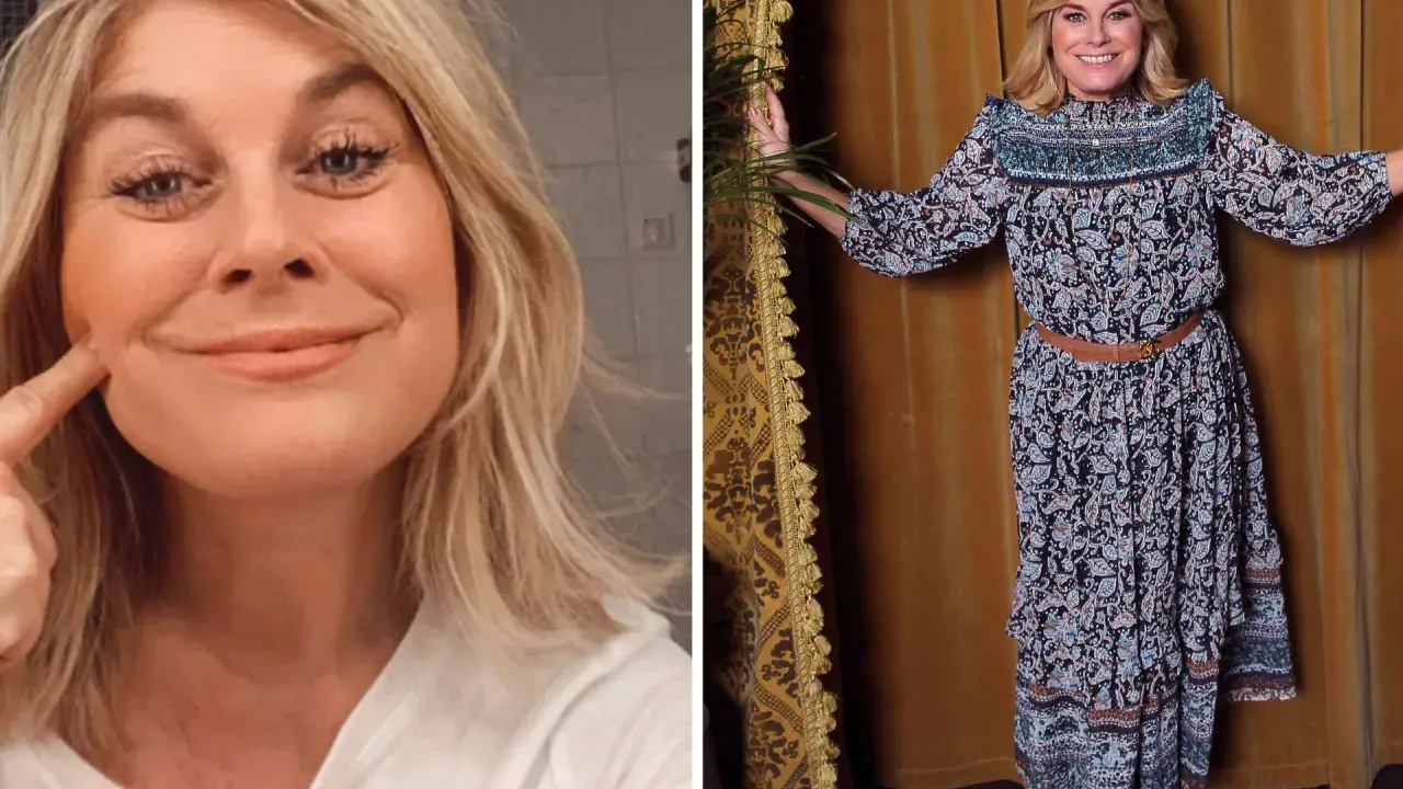 Pernilla Wahlgren ler och pekar på sitt ansikte. Hon bär en mönstrad klänning och ser glad ut.
