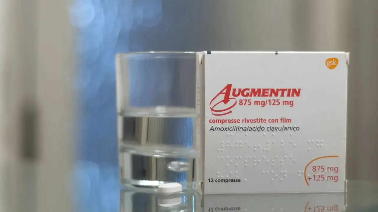 Szklanka wody obok opakowania Augmentin. Pamiętaj, że augmentin i alkohol to nie najlepsze połączenie.