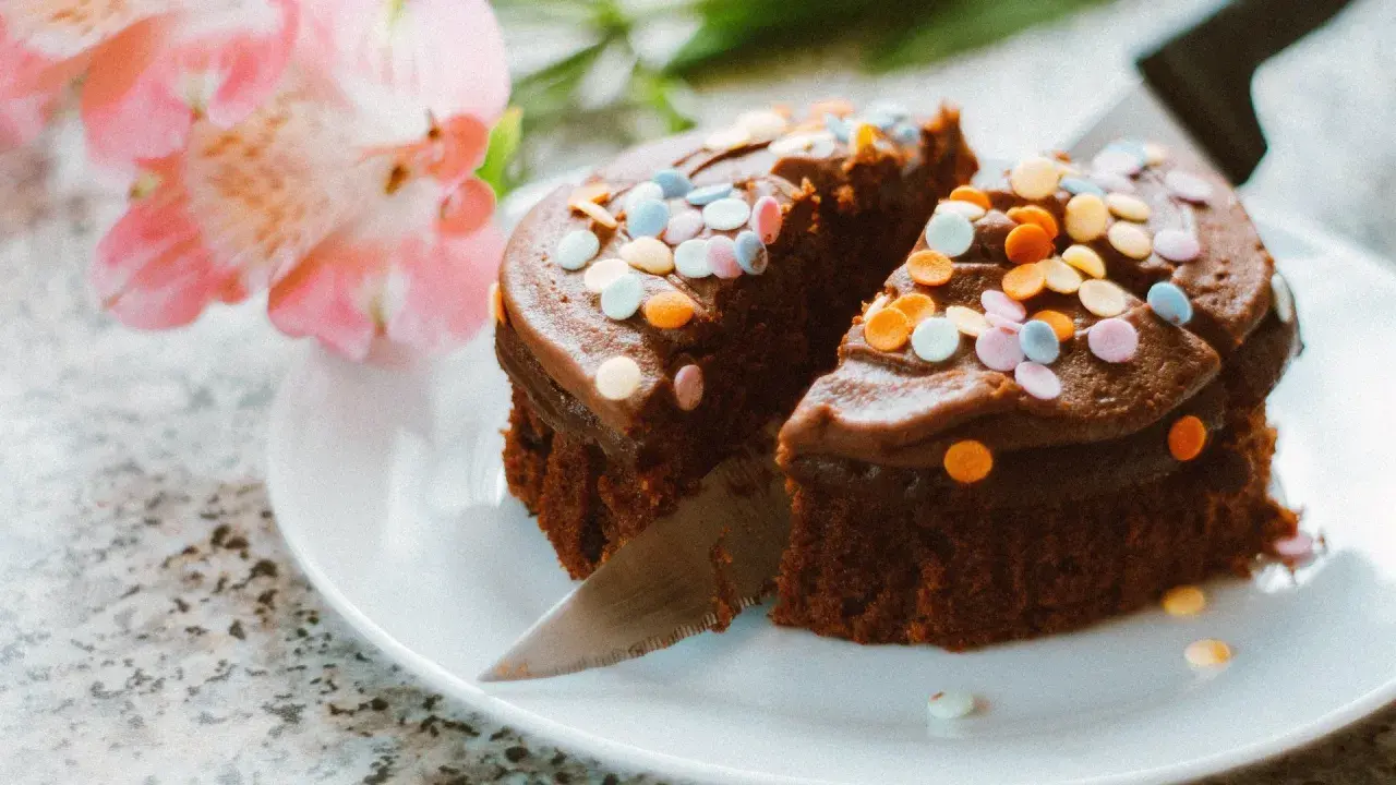 Schokoladenkuchen mit bunten Streuseln, angeschnitten. Eine kreative Idee, um Kuchenreste verwerten und nochmals genießen zu können.