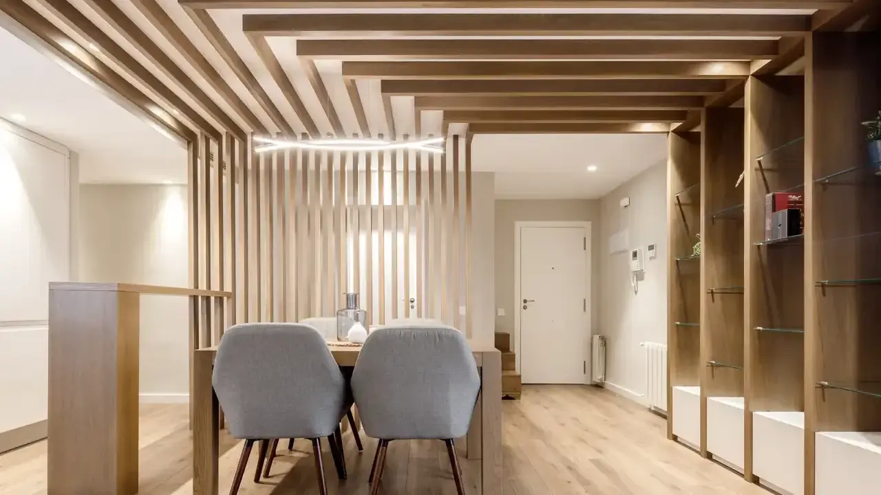 Comedor moderno con separador de listones de madera y estanterías. Preguntarse cuanto se tarda en tirar un tabique es irrelevante aquí.