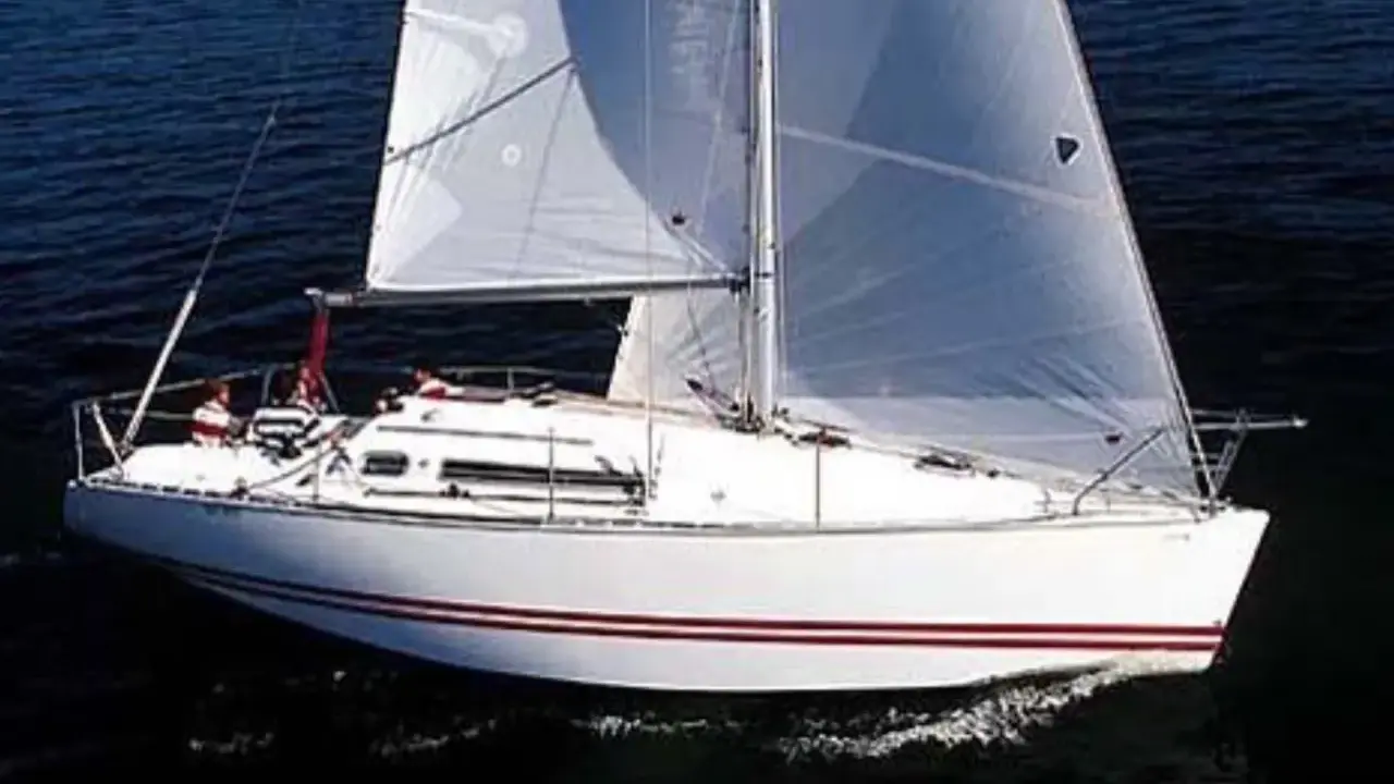 Voilier blanc à voiles gonflées, naviguant sur l'eau sombre. Les avis sur le Sun Fast 32 confirment sa rapidité.