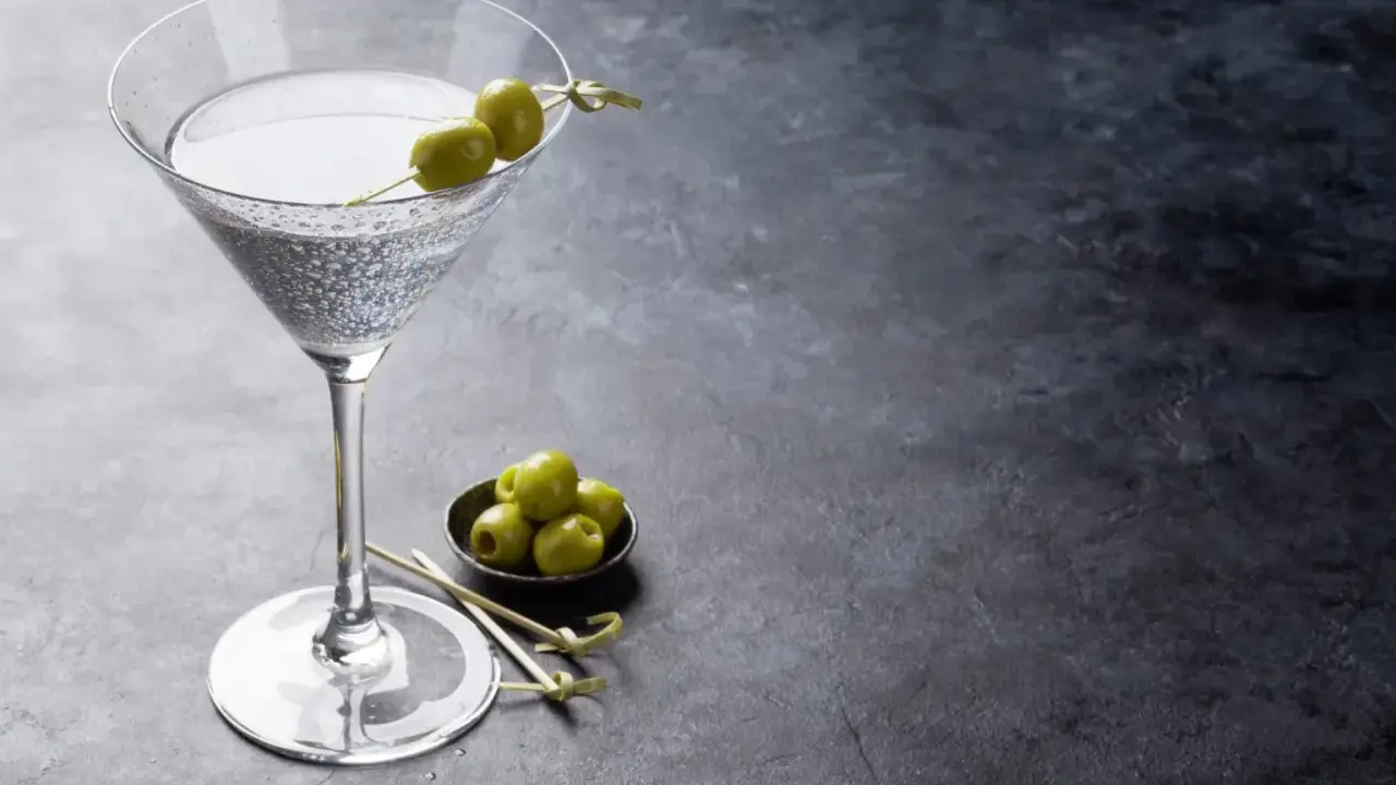 Un verre de dry martini, garni de deux olives, prêt à être dégusté. La recette parfaite pour un apéritif chic.