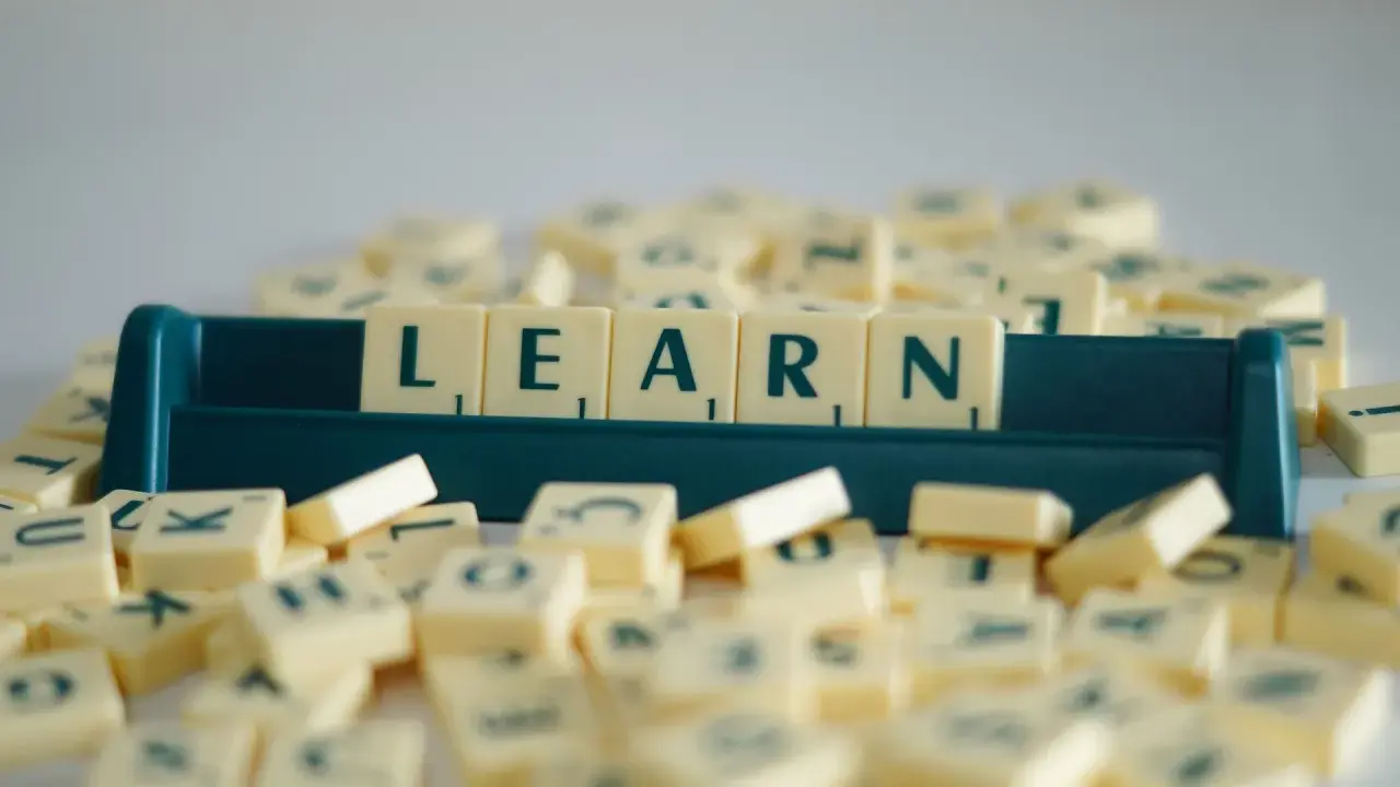 Litery na kafelkach układają się w słowo LEARN, symbolizując naukę i rozwijanie słownictwa. To świetny przykład na word formation C1.