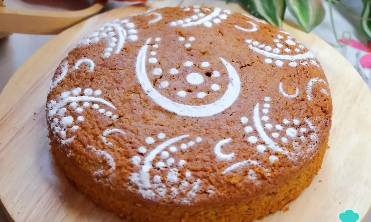 Bizcocho de zanahoria decorado con azúcar glas en un diseño de lunas y puntos. Se ve delicioso y esponjoso.