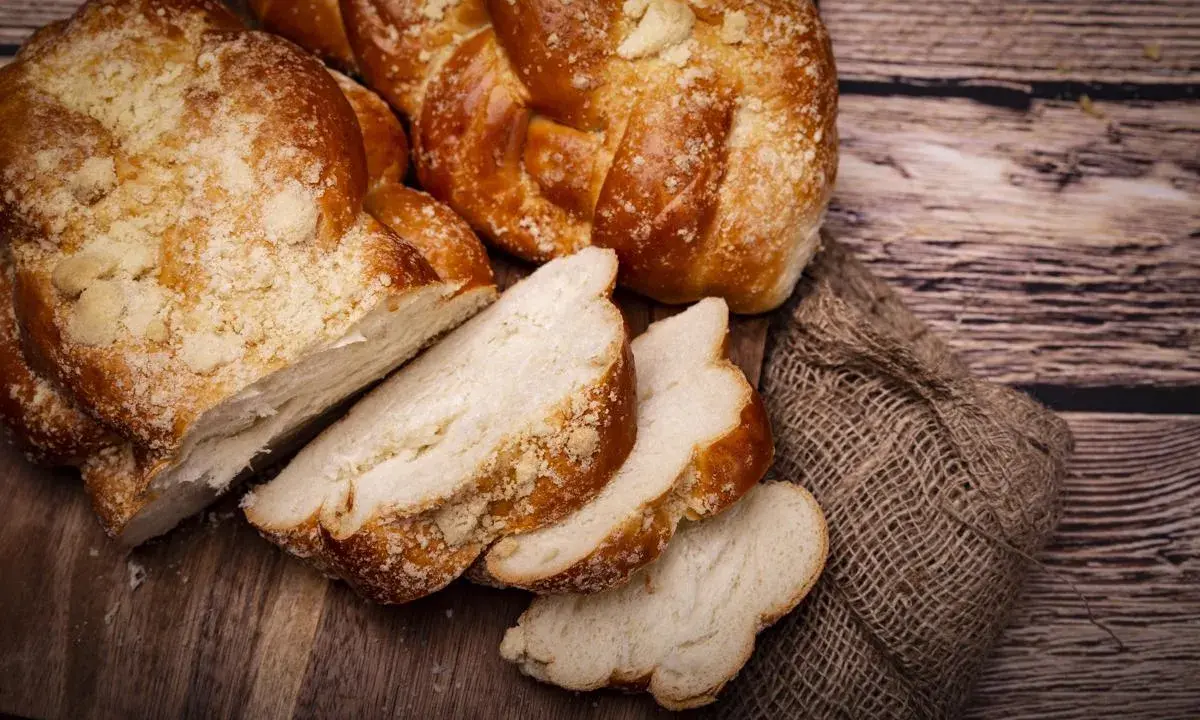 Puszyste ciasto drożdżowe, pokrojone w kromki, na drewnianej desce. Dowiedz się, jak przechowywać ciasto drożdżowe, by było świeże.