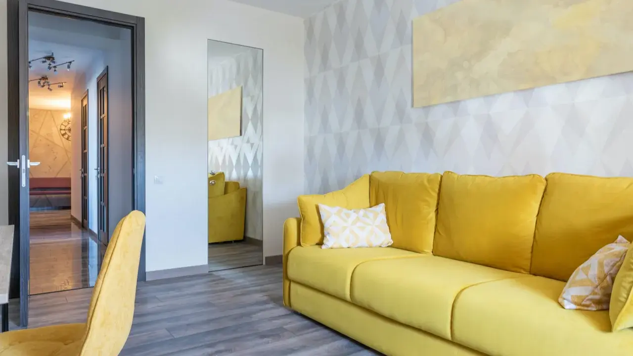 Un sofá amarillo vibrante y un sillón a juego llenan la habitación, destacando los alegres colores de sofás.