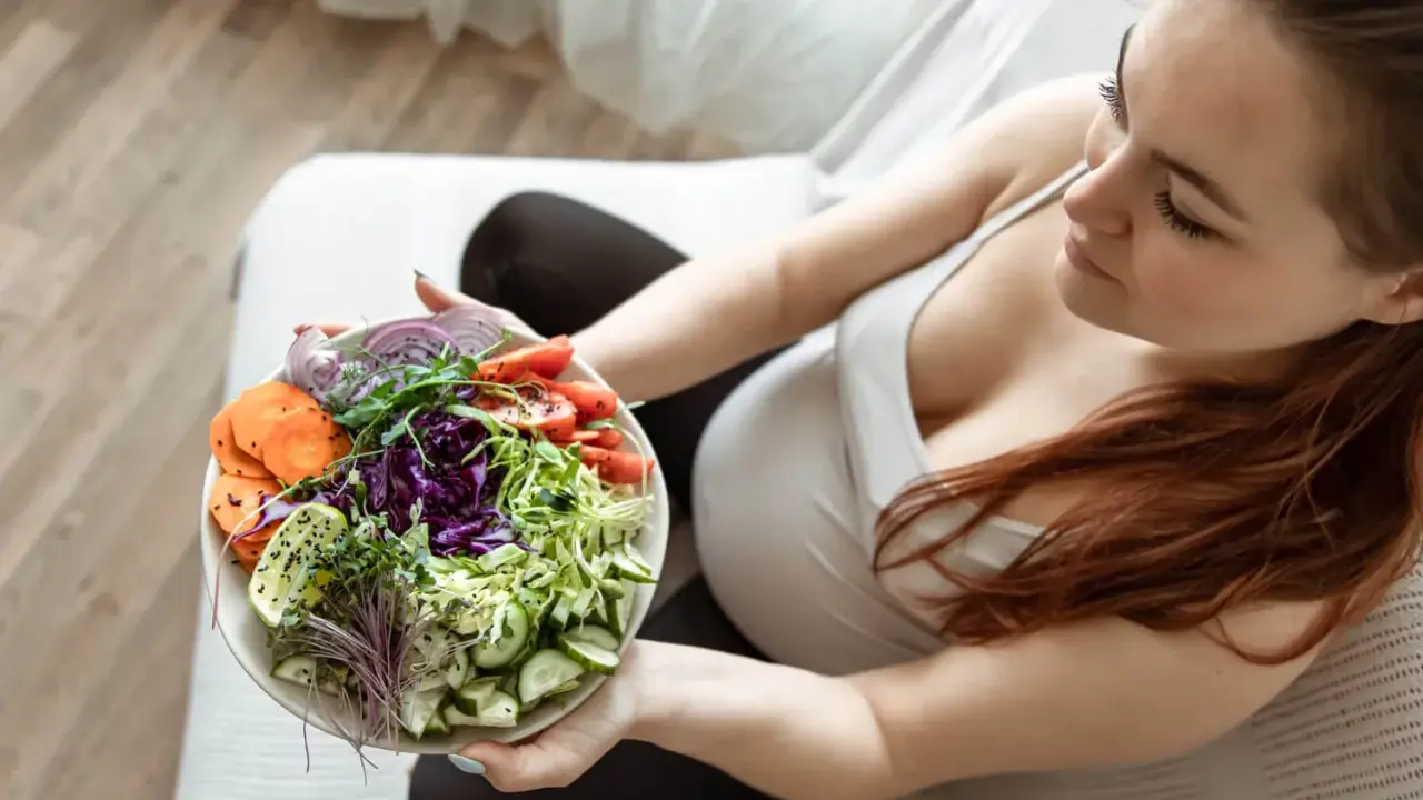 Kobieta w ciąży delektuje się zdrową sałatką, dbając o dietę w ciąży. Kolorowe warzywa to podstawa.