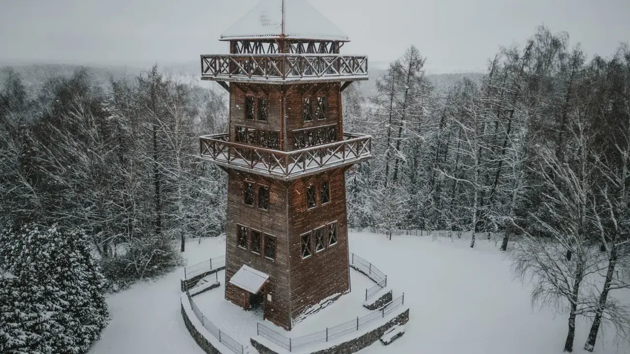 Drewniana wieża widokowa na Mazurach w zimowej scenerii. Otoczona ośnieżonym lasem, zaprasza do podziwiania krajobrazu.