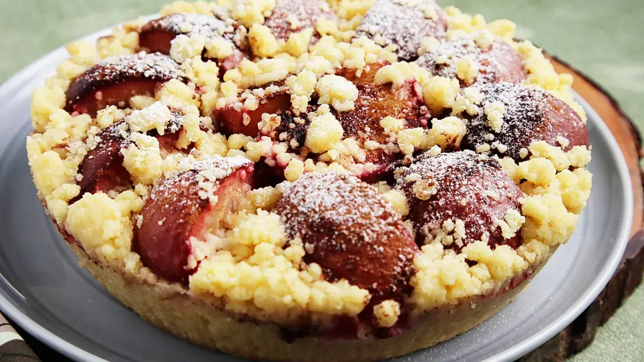 Ein köstlicher pflaumenkuchen ohne hefeteig, bestreut mit Puderzucker und knusprigen Streuseln.