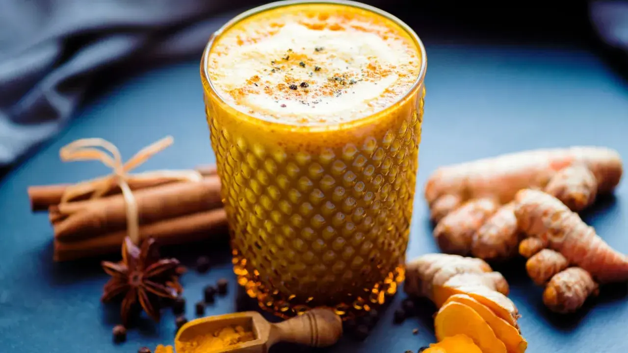 Ein Glas goldene Milch mit Kurkuma, Ingwer, Zimt und Sternanis. So wird goldene Milch gemacht.