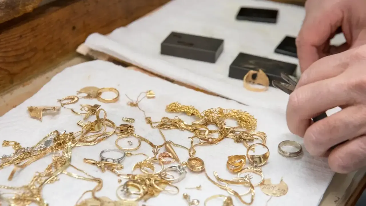 Mani esperte valutano gioielli d'oro, anelli e collane, un modo pratico per imparare come riconoscere l'oro.