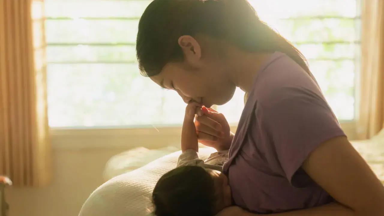 Dolce momento tra madre e neonato. La mamma bacia la manina del piccolo, attenta ai suoi segnali fame.
