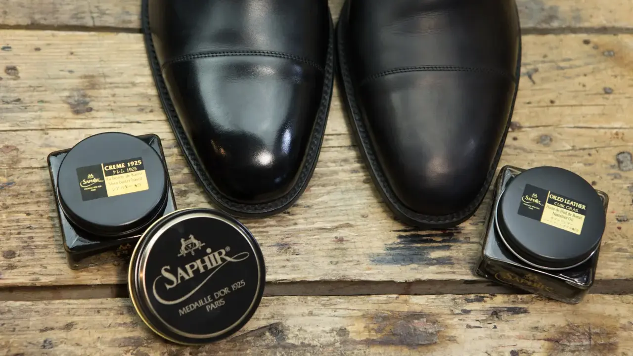 Czarne, eleganckie buty i dwa słoiczki Saphir: krem do skóry i olejek. Idealne, by dowiedzieć się, czym natłuścić skórzane buty.