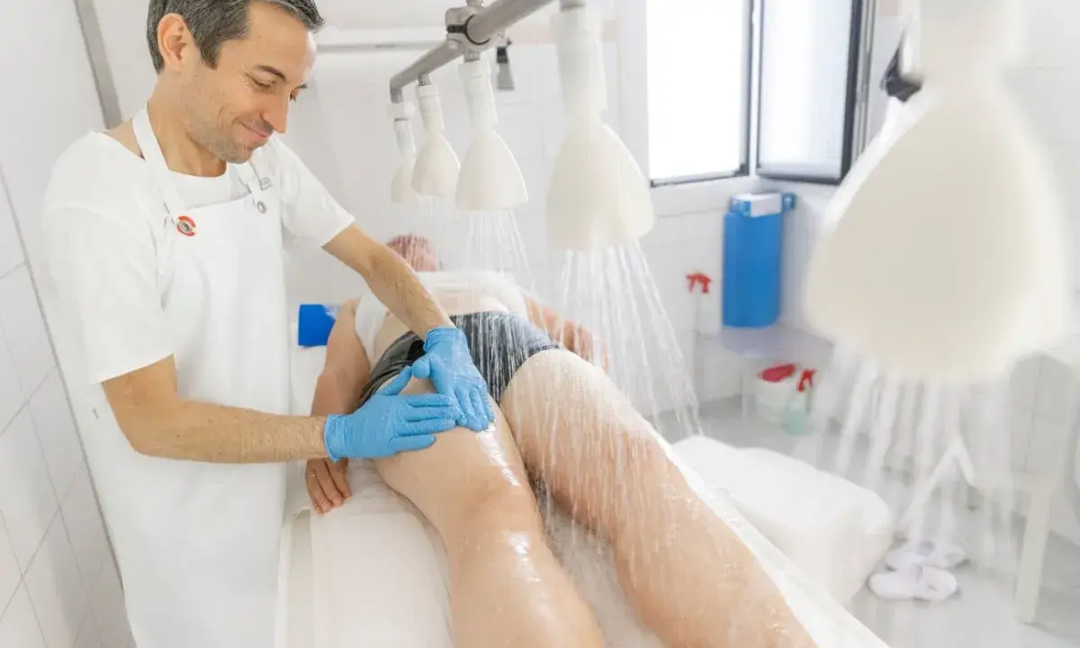 Un thérapeute masse les jambes d'un patient sous une douche à jets multiples, une thérapie par **avene les bains** pour la relaxation et la guérison.