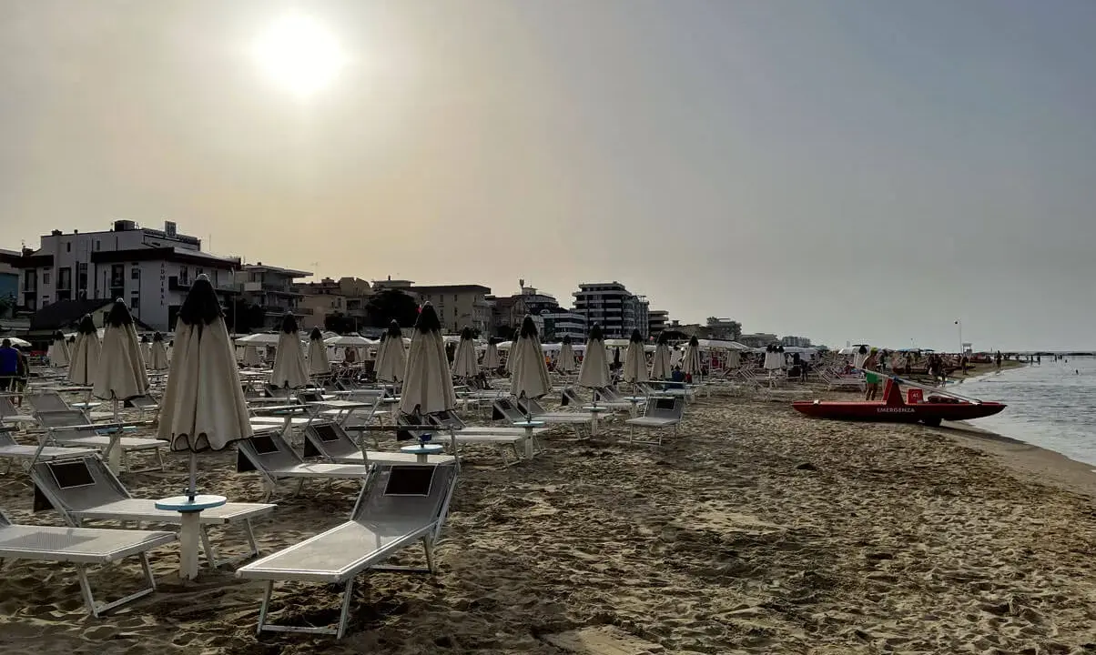 Spiaggia di Igea Marina con lettini e ombrelloni chiusi, bagnino pronto con la sua imbarcazione sul mare calmo.