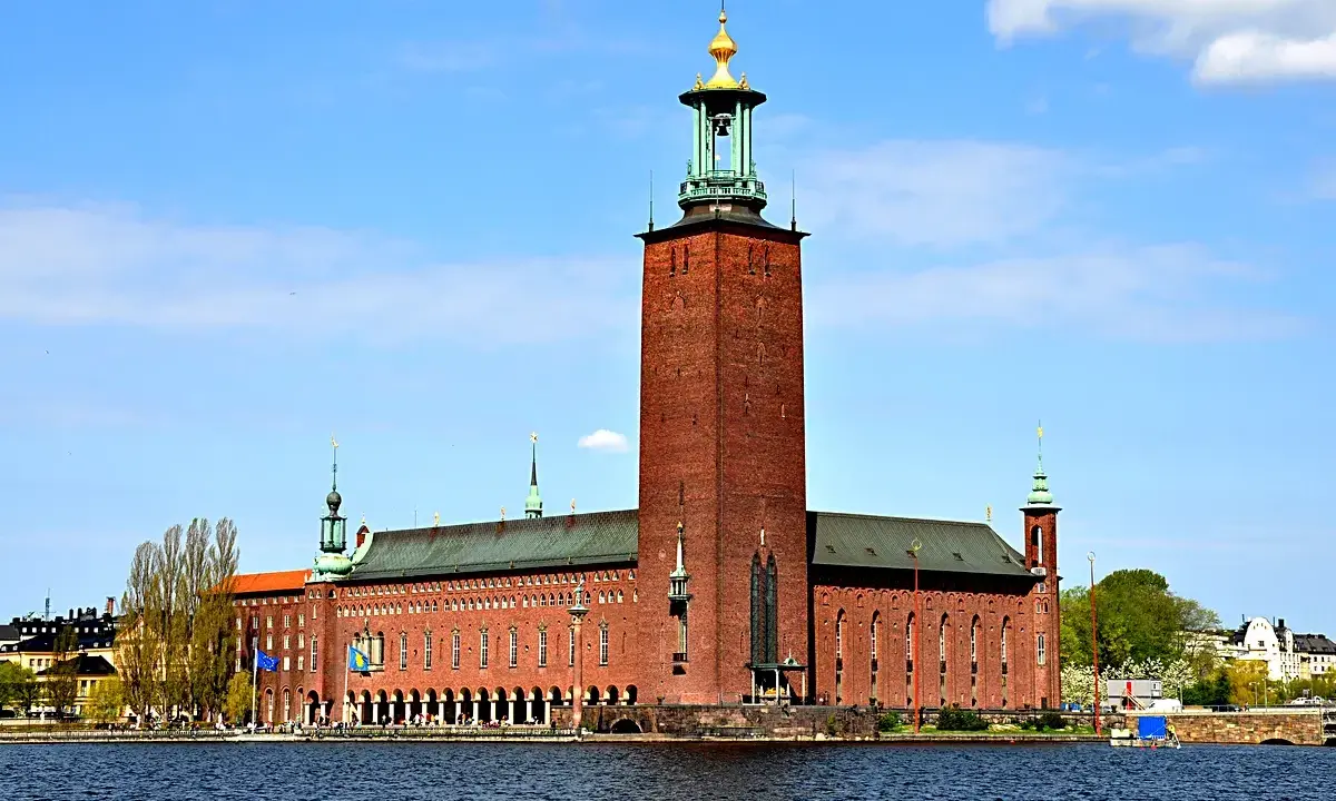 Stockholms stadshus reser sig stolt vid vattnet, dess ikoniska torn dominerar horisonten.