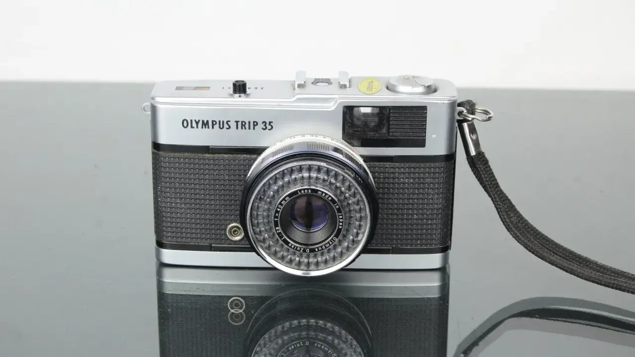 Cámara Olympus Trip 35 plateada con correa negra, lista para tu próxima aventura.