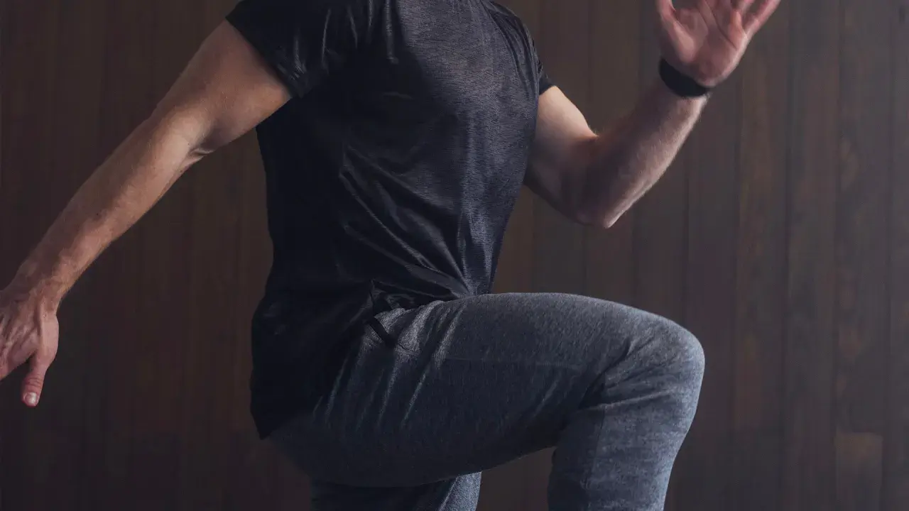 Mann in Sportkleidung, der auf der Stelle läuft, um sich aufzuwärmen.