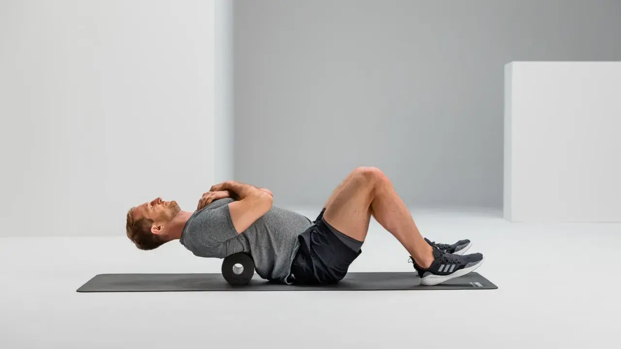 Mann macht Foam Rolling auf einer Matte, um seinen Rücken zu entspannen.