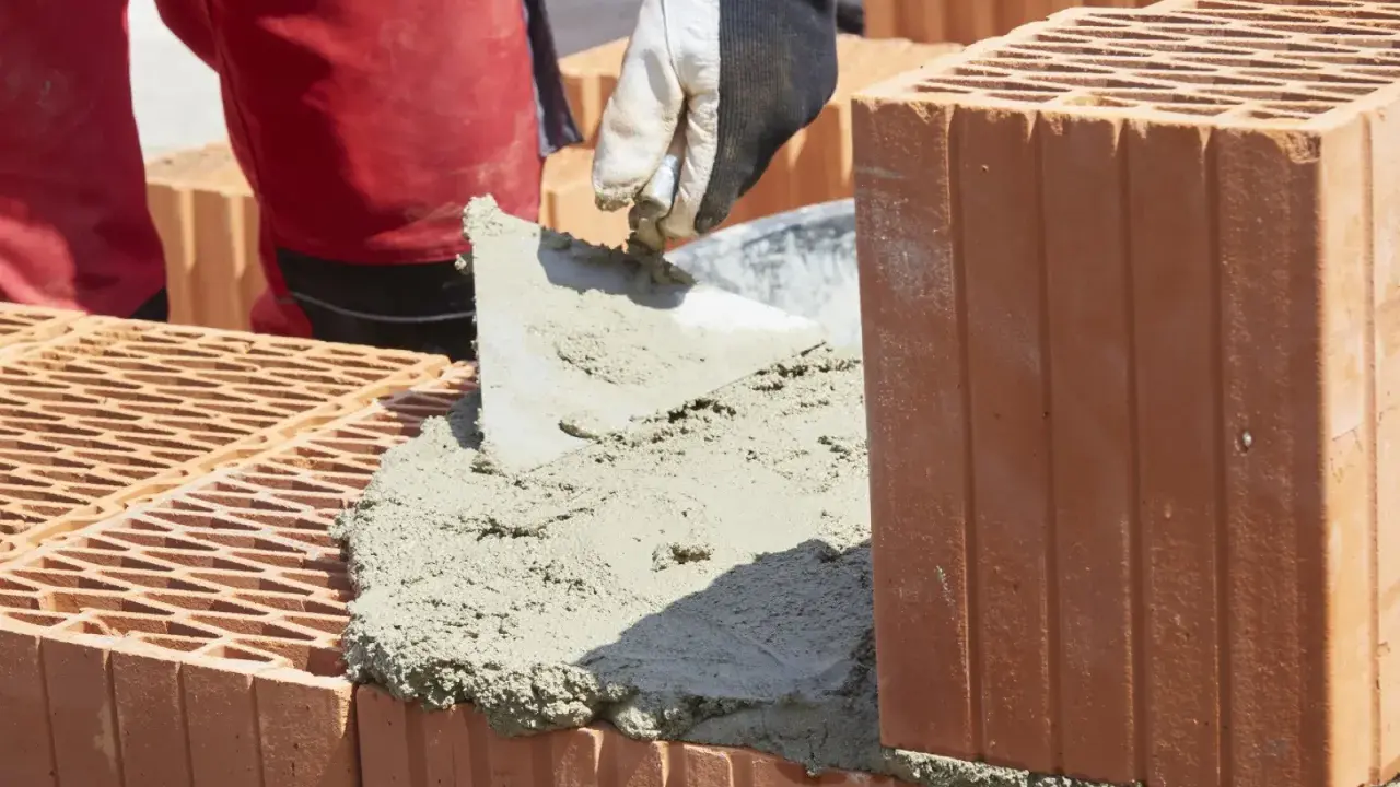 Budowanie muru z pustaków ceramicznych, nakładanie zaprawy. Właśnie tak jak zrobic cement do budowy.